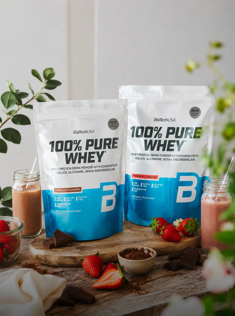 Proteína 100% Pure Whey Biotech USA em promoção até 26%, apresentada com batidos, morangos e chocolate num cenário de cozinha.